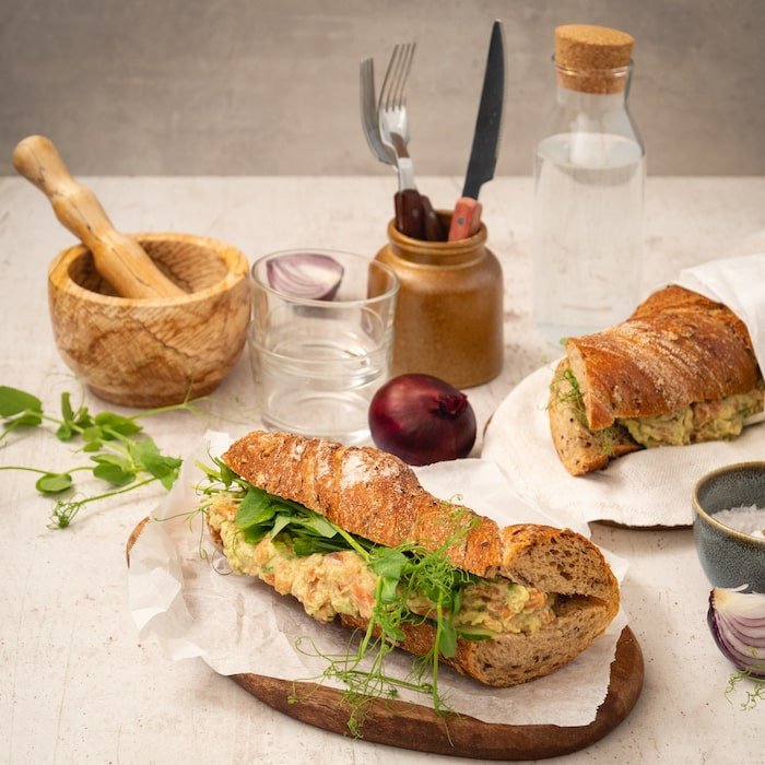 Raikas hummus-limebaguette lohella ja avokadolla ruokapöydässä